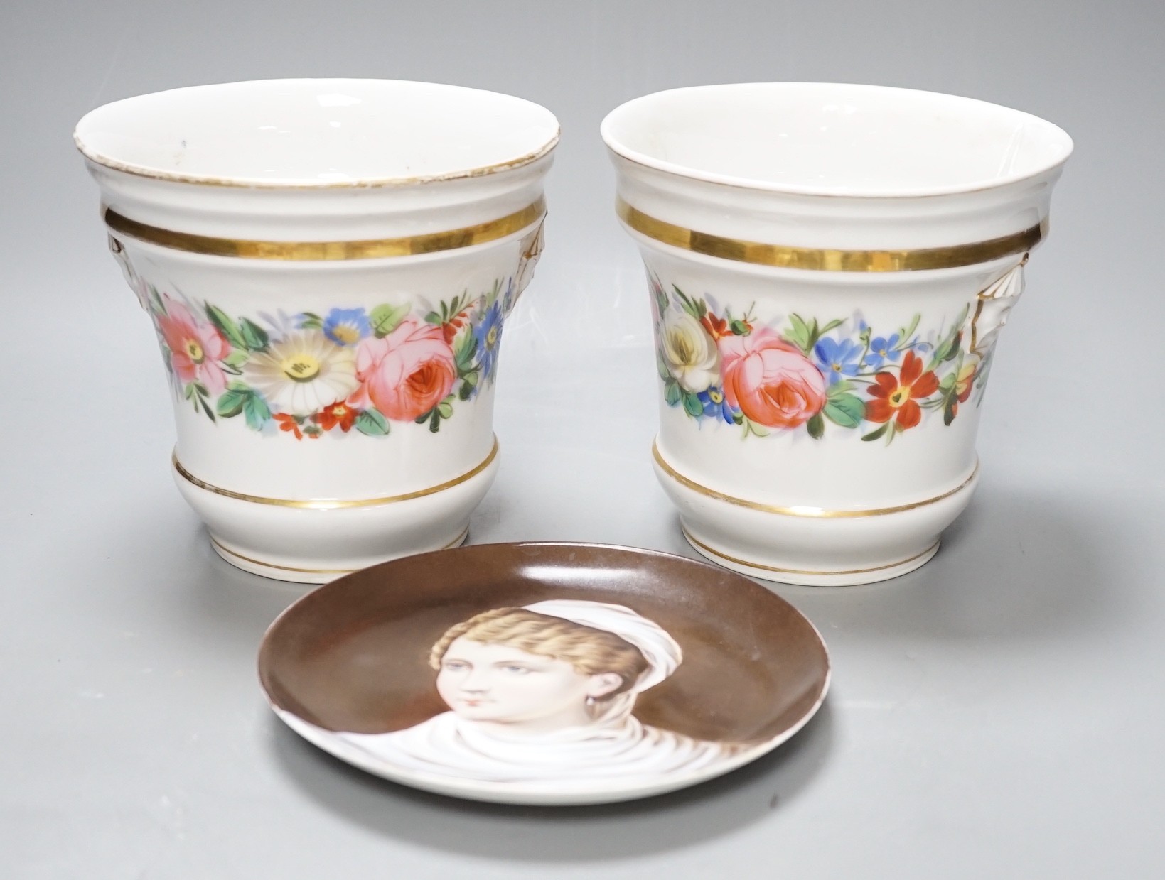 A 19th century pair of Paris porcelain flowers pot with Chinese figural heads, a chain of flowers and four gilt bands and a Continental circular plaque painted with a lady on a brown ground, flower pots 14.5 cms high